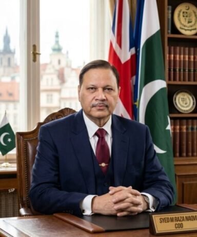 Syed M Raza Naqvi, COO, seated at his desk with flags behind him.